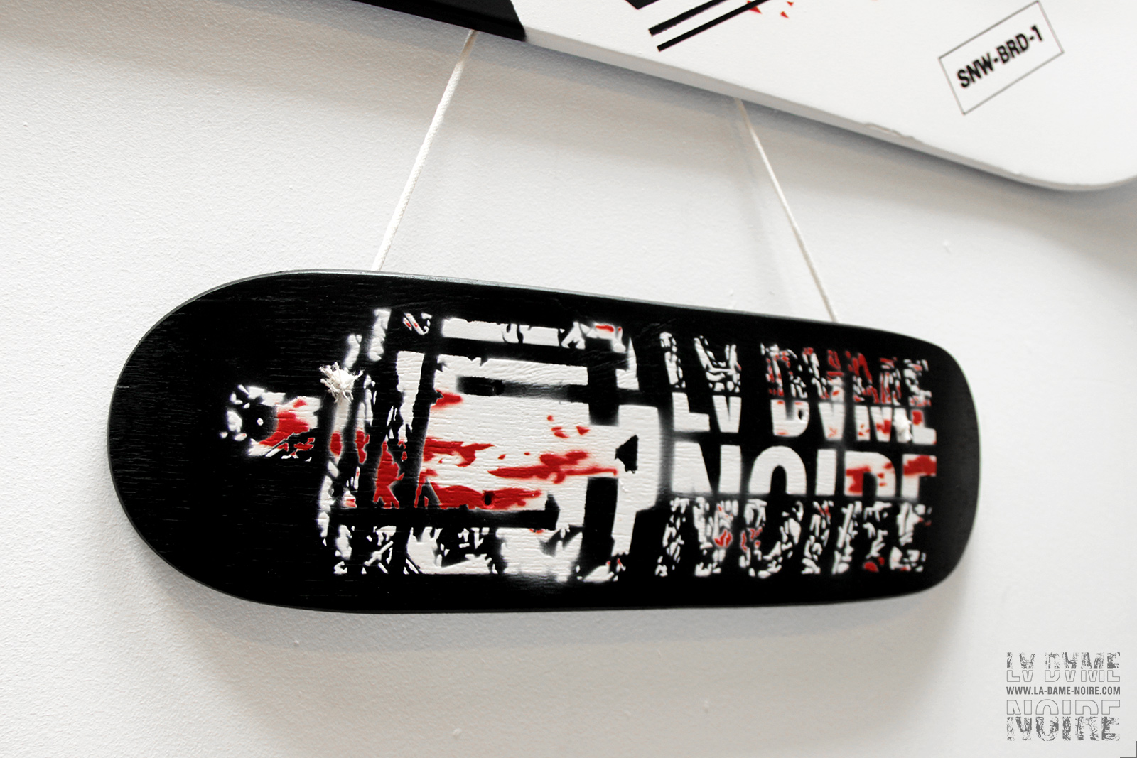 Tiny-skateboard painted in black and white with La Dame Noire's logo